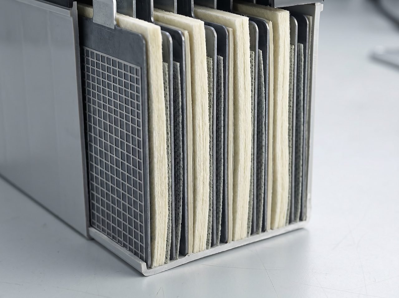 cutaway cross-section showing compressed fiberglass mat between lead plates inside a sealed AGM battery