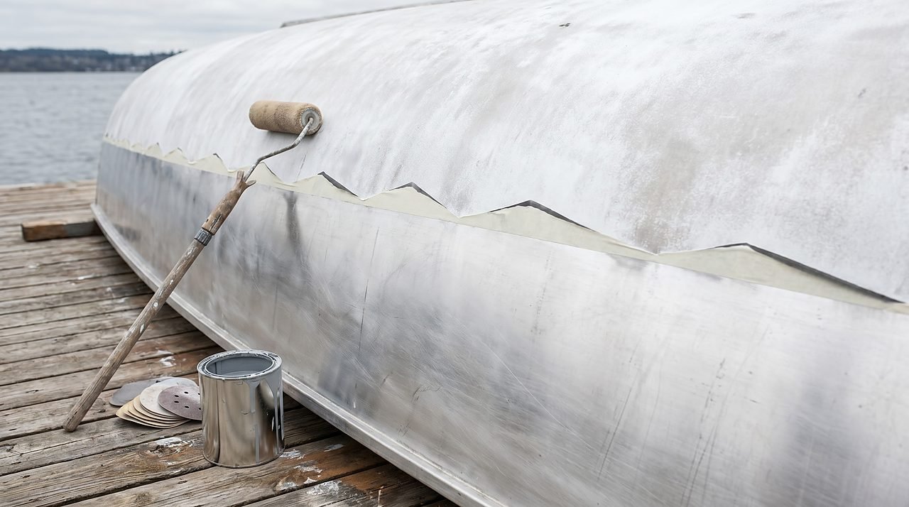 oxidized aluminum boat hull being restored with sanding and epoxy primer preparation at dock