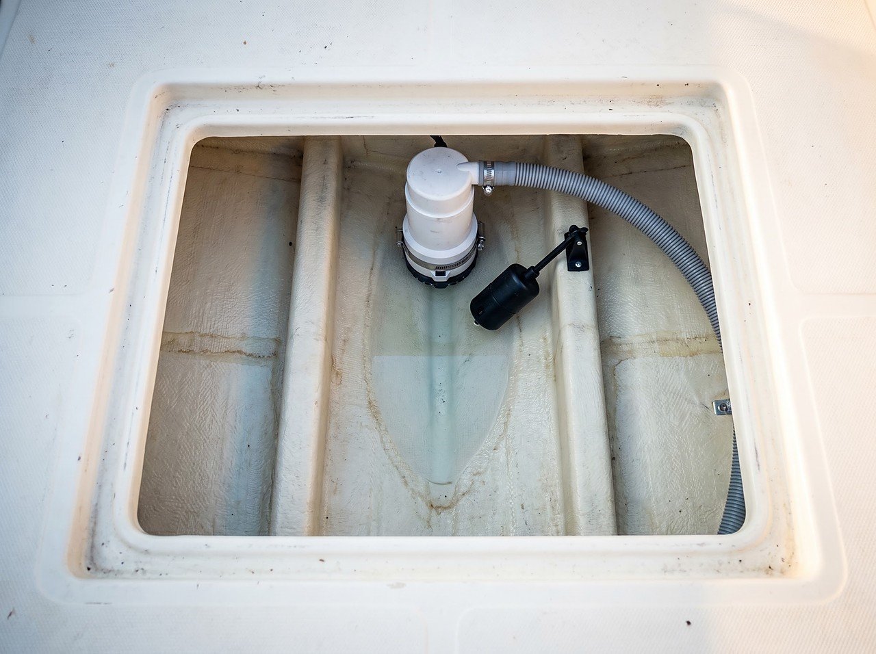 boat bilge pump and float switch visible through open access hatch during post-trip inspection