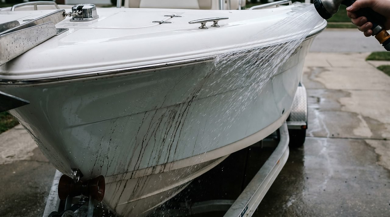 fresh water rinse removing salt grime from a fiberglass boat hull before washing