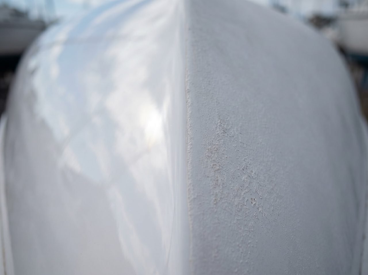 close-up of gelcoat showing glossy waxed surface beside chalky UV-oxidized unprotected hull