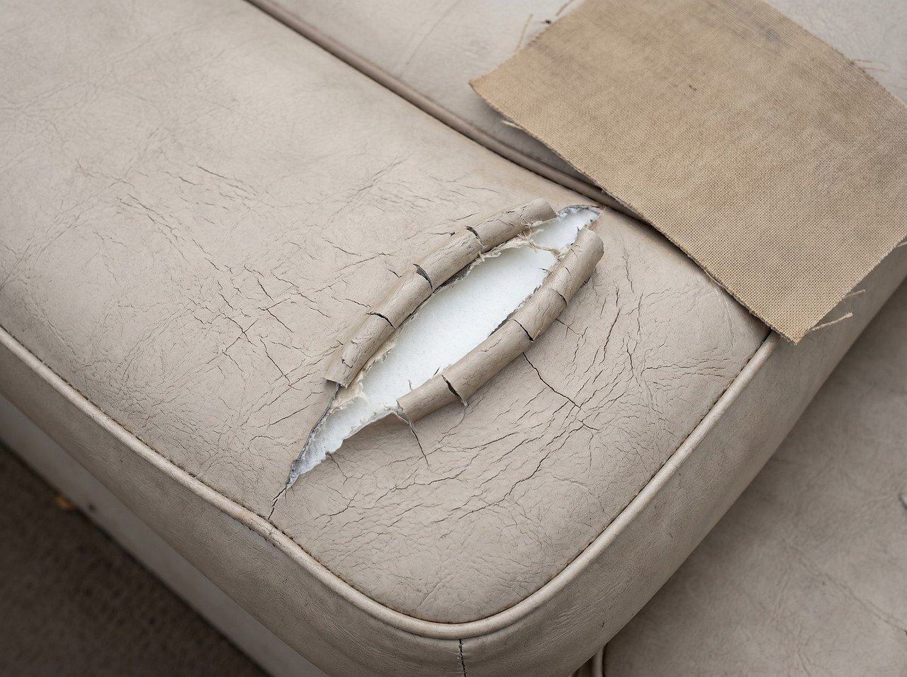 torn corner on an aged marine vinyl boat seat with foam exposed and surface crazing visible