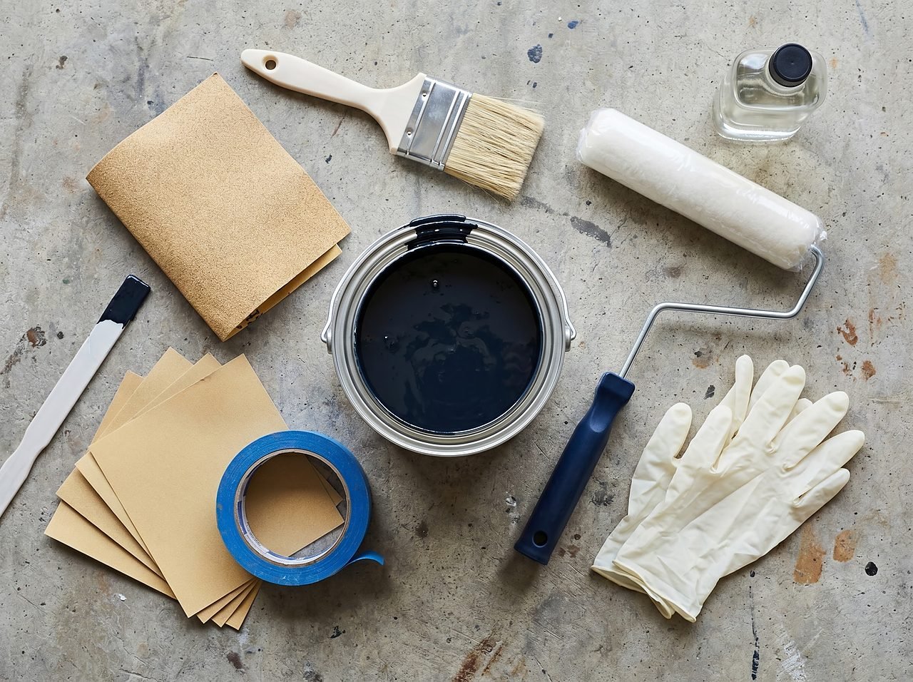 bottom paint materials laid out on a workbench including paint can, roller, sandpaper, and tape