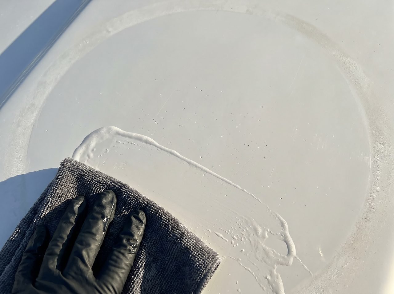 fiberglass gelcoat surface showing wax being stripped by a soapy wash cloth