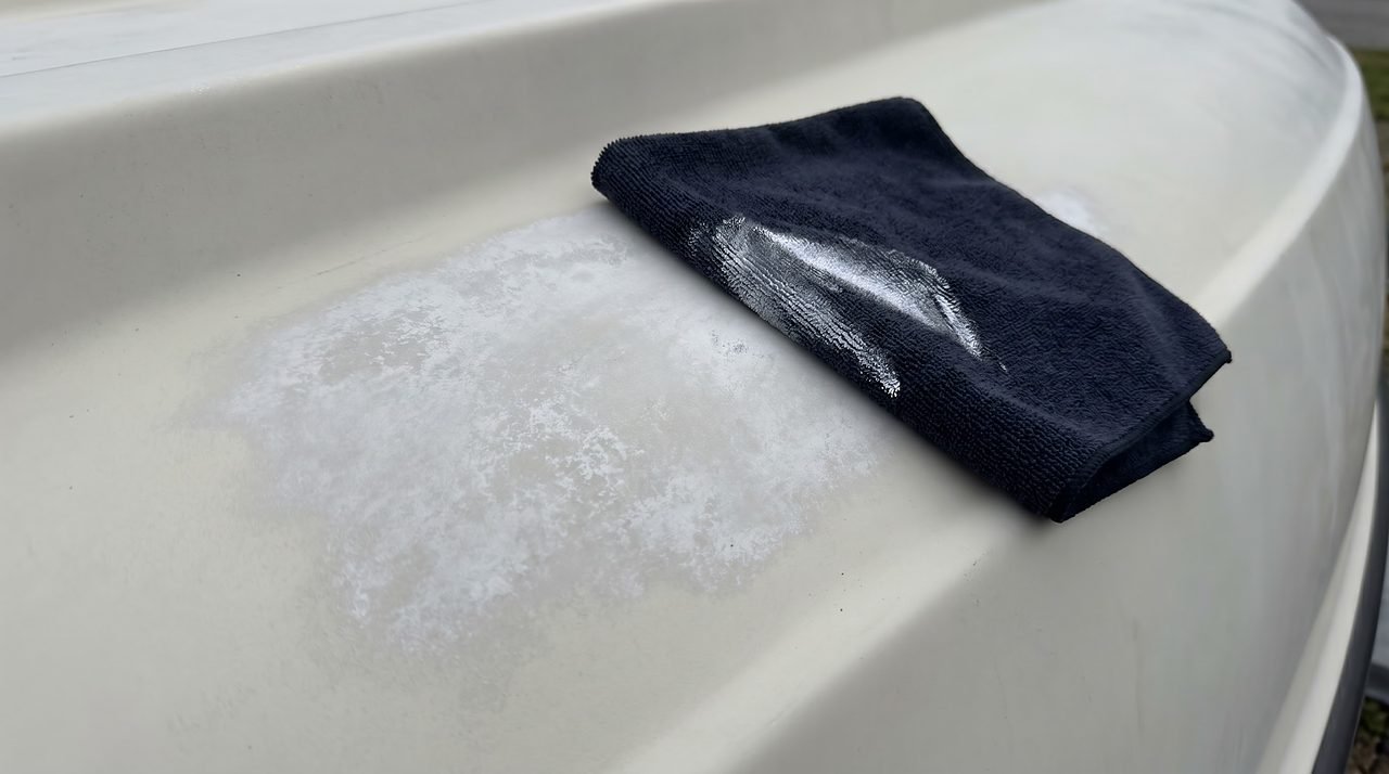 dark microfiber cloth showing white chalk residue after palm-rub test on oxidized gelcoat