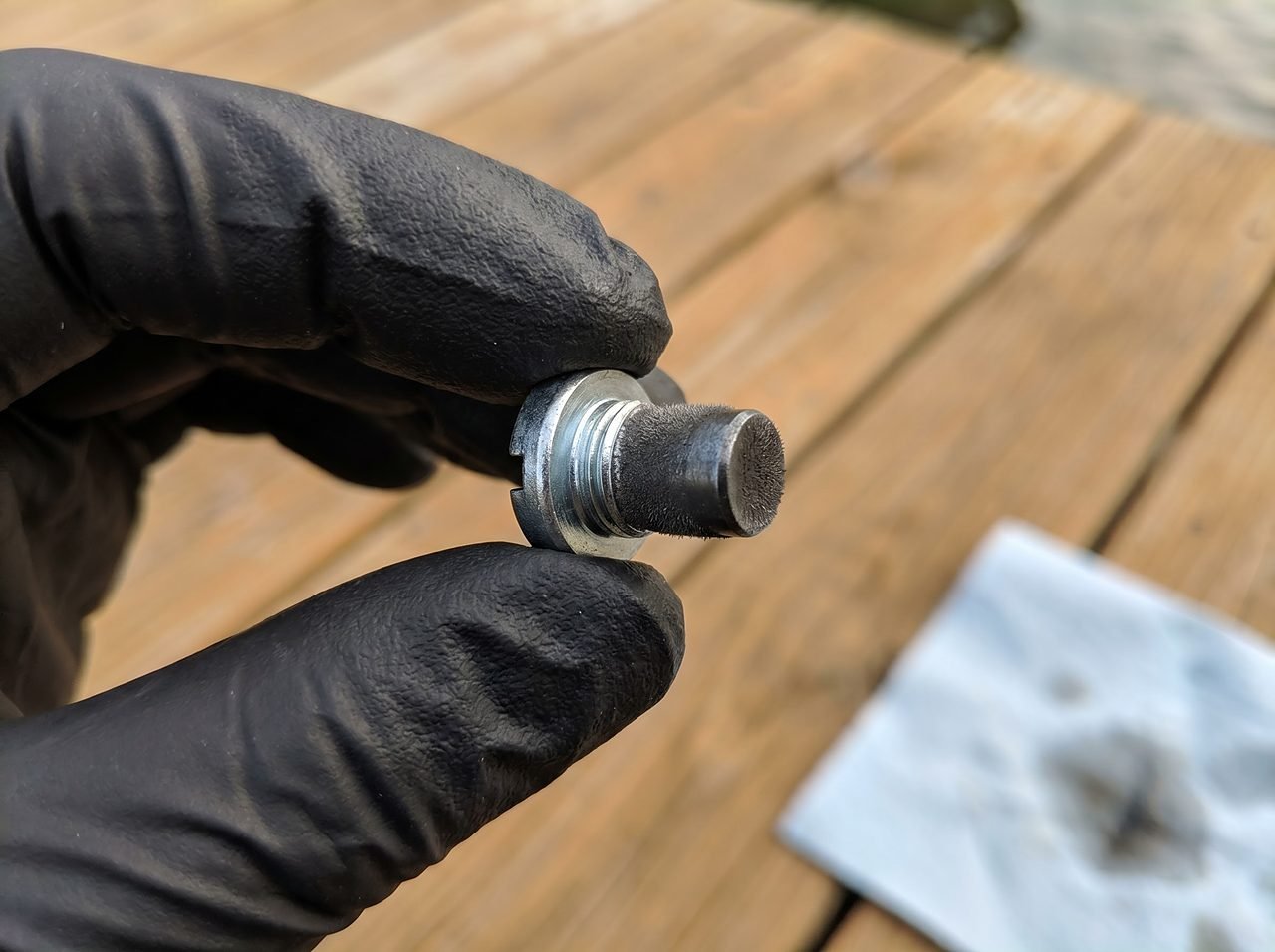 Magnetic drain plug tip showing fine metallic powder residue from normal outboard gear wear