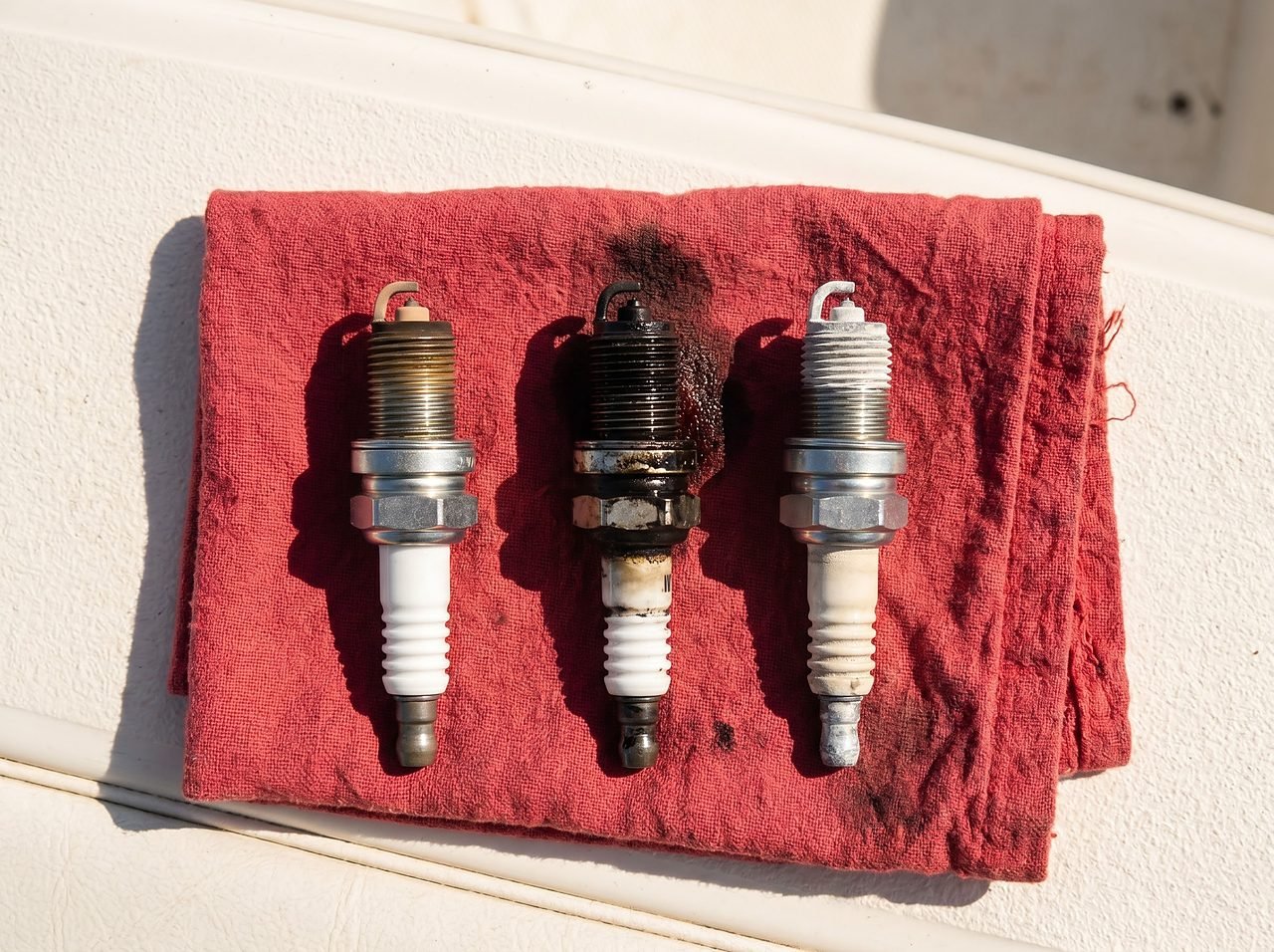 three outboard spark plugs showing normal, fouled, and overheated conditions side by side
